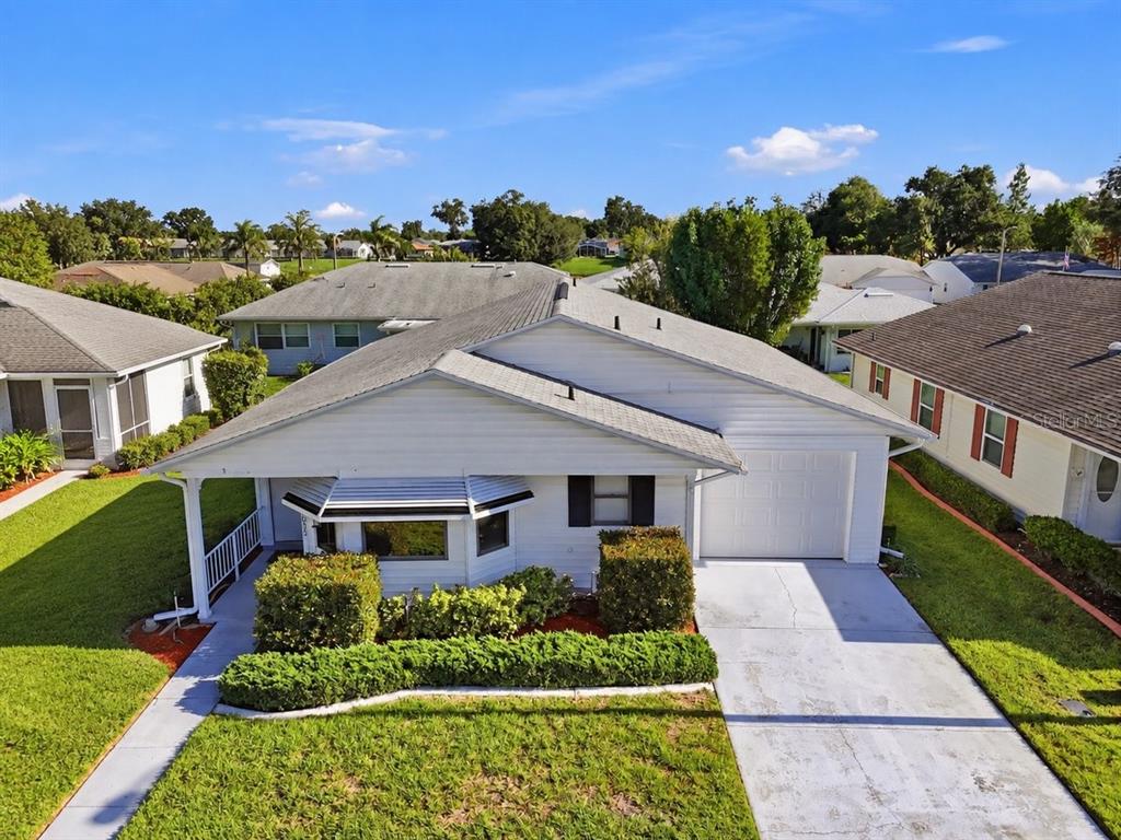 A white single-story house with horizontal siding, a front porch, and manicured landscaping — 2033 LONG BOAT DRIVE, LAKELAND, FL