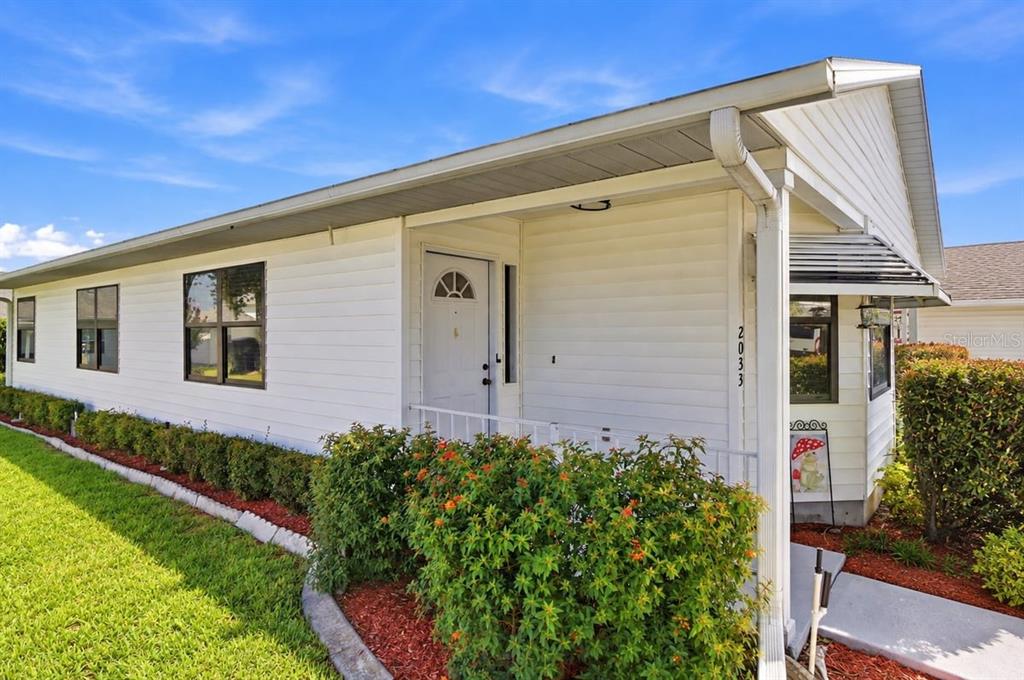 A white, single-story house with a concrete driveway, attached garage, and manicured landscaping — 2033 LONG BOAT DRIVE, LAKELAND, FL