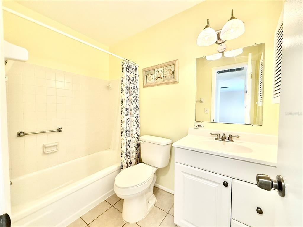 A bathroom features a white vanity, a toilet, and a shower-tub combination with tiled walls — 6105 CORAL WAY, BRADENTON, FL