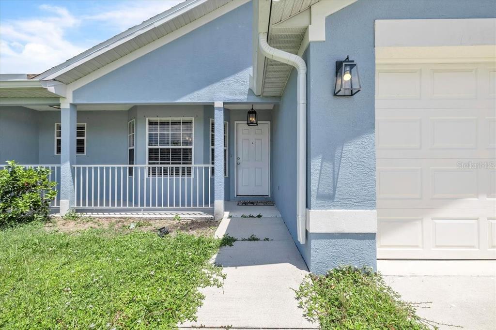 A blue house exterior features a white front door, a garage, and a concrete walkway — 1708 BLUE LAKE CIRCLE, PUNTA GORDA, FL