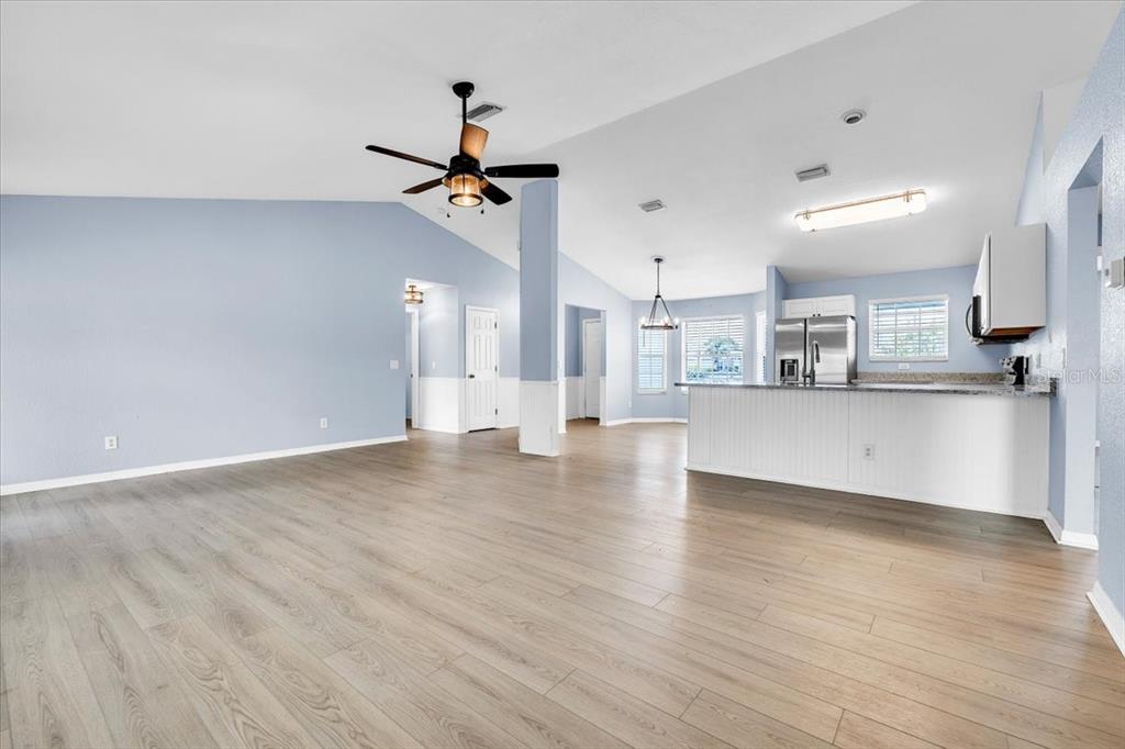 An open-concept living area features light blue walls, wood-look flooring, and a kitchen island — 1708 BLUE LAKE CIRCLE, PUNTA GORDA, FL