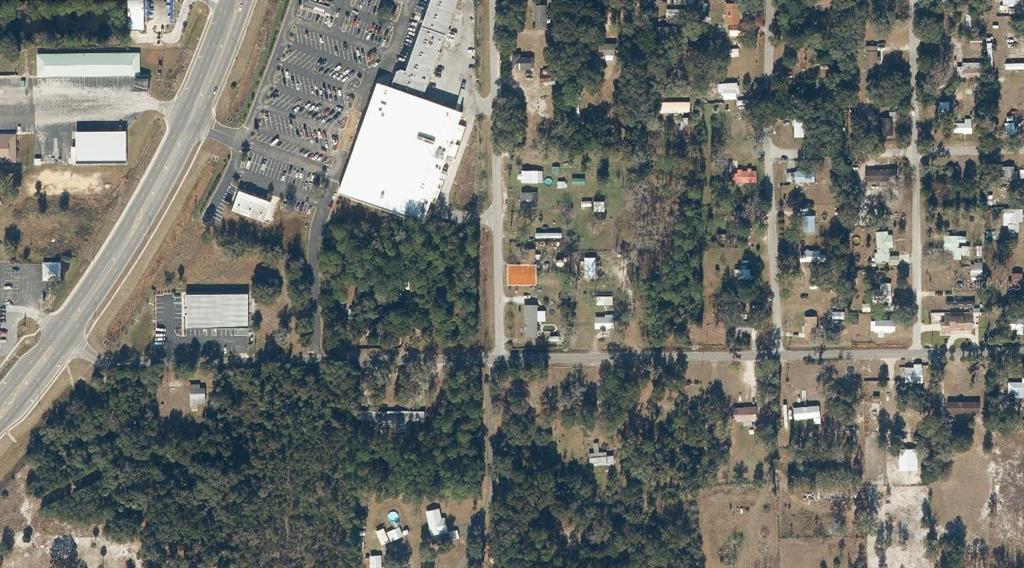 This aerial view shows a residential area adjacent to a commercial parking lot and building — 310 FLORIDA DRIVE, PALATKA, FL