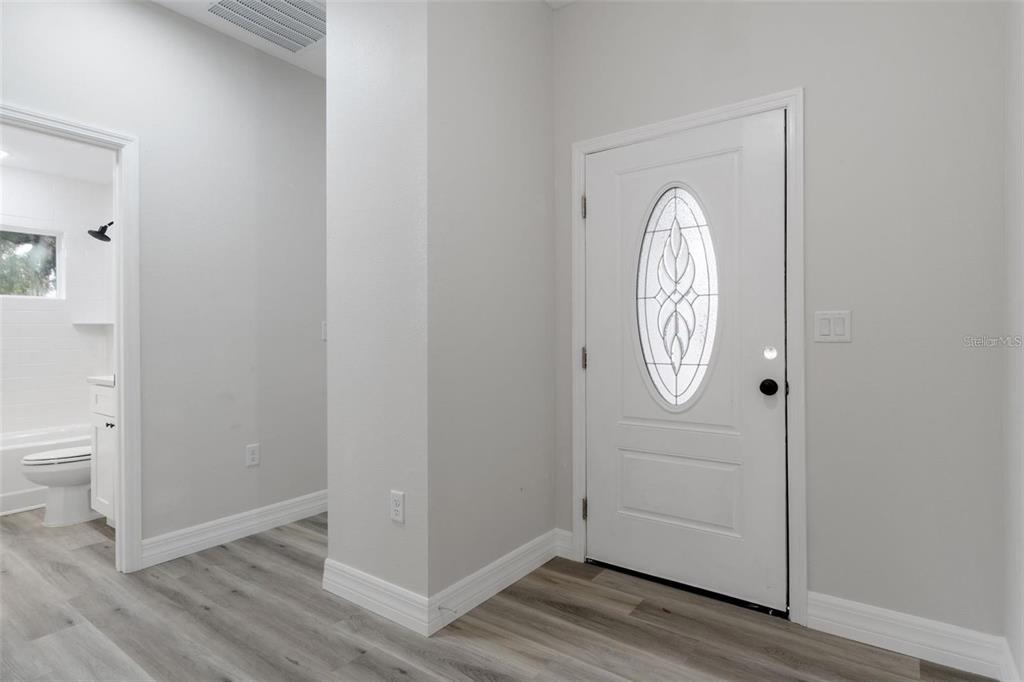 A white front door with an oval glass insert opens to a room with light flooring — 3248 E PORTER STREET, INVERNESS, FL