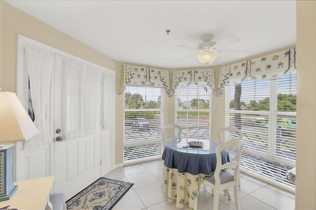 A sunlit breakfast nook features tile floors, a round table, and large windows with valances — 11000 PLACIDA ROAD UNIT 1801, PLACIDA, FL