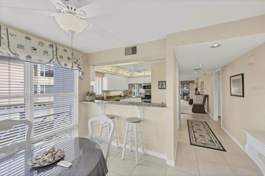 A dining area with a breakfast bar overlooks a kitchen with white cabinets and appliances — 11000 PLACIDA ROAD UNIT 1801, PLACIDA, FL