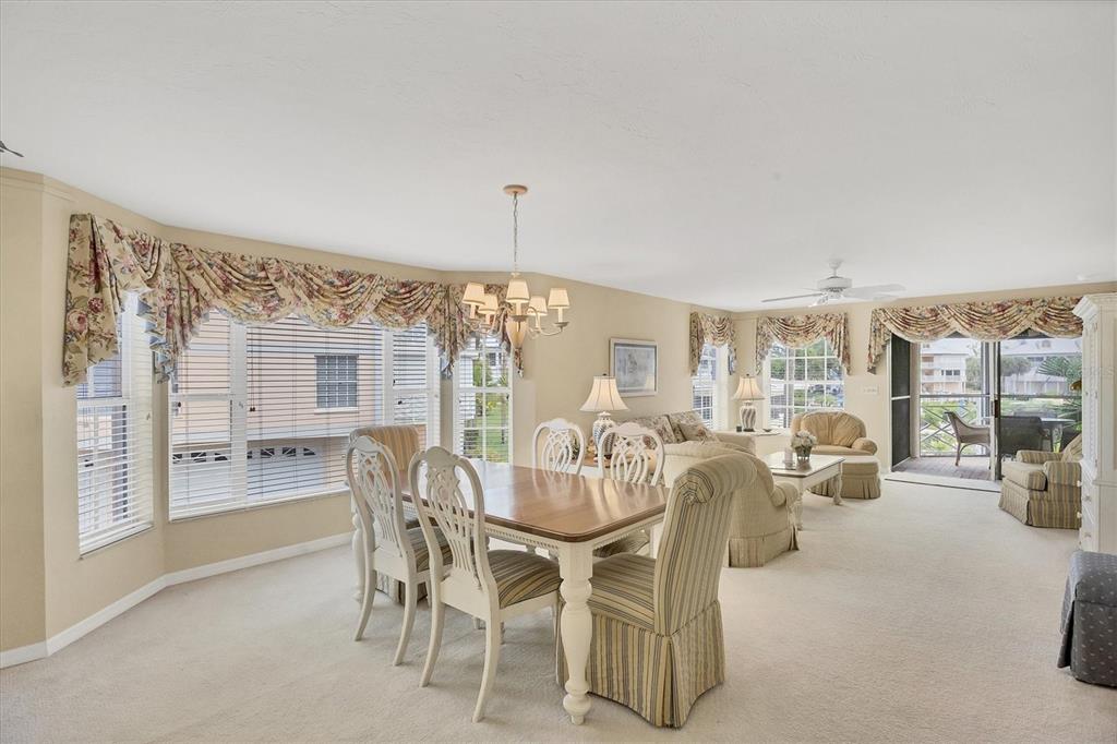 A dining area and living room feature beige carpeting, neutral walls, and floral window valances — 11000 PLACIDA ROAD UNIT 1801, PLACIDA, FL