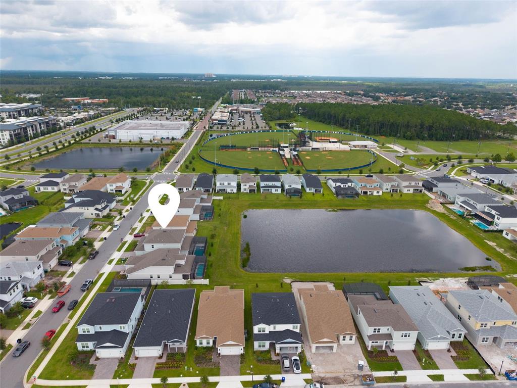 An aerial view shows a residential neighborhood with houses, a large pond, and a baseball field — 8369 FENTON STREET, ORLANDO, FL