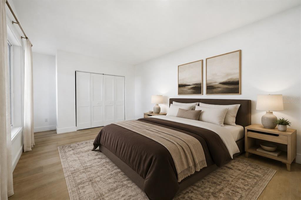 An empty room with white walls, wood-look flooring, and large windows overlooking a neighborhood street — 2317 GROVE STREET, SARASOTA, FL