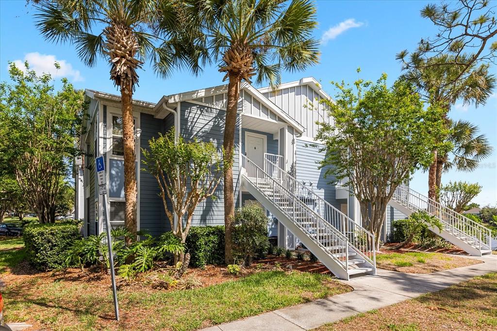 An aerial view shows a multi-story apartment building with a parking lot beside a lake — 2501 GRASSY POINT DRIVE UNIT 103, LAKE MARY, FL
