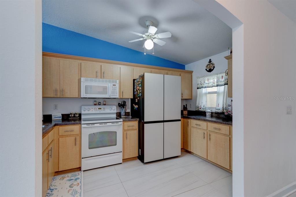 A covered entryway features a white door, tiled floor, screen door, and a Steelers umbrella stand — 2246 HAWKS COVE CIRCLE, NEW SMYRNA BEACH, FL