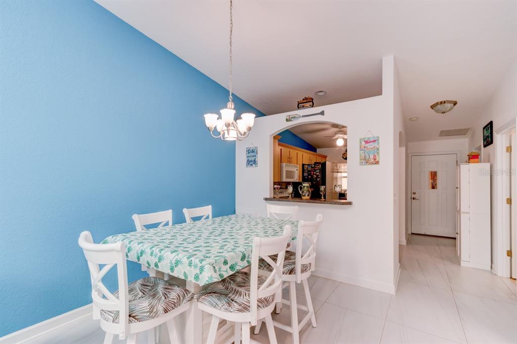 A living room features white tile floors, blue armchairs, teal shelving, and a large mermaid mural — 2246 HAWKS COVE CIRCLE, NEW SMYRNA BEACH, FL