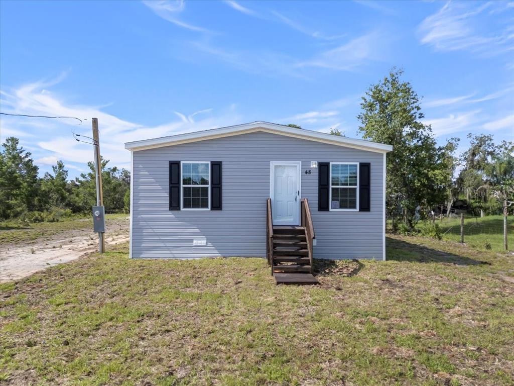 A single-story gray manufactured home with black shutters and wooden front steps — 2763 N VASSER TERRACE, HERNANDO, FL