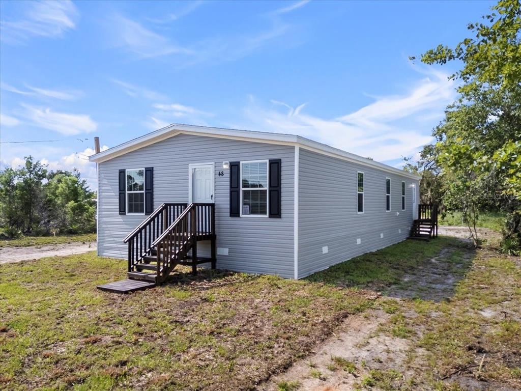 A light gray manufactured home with dark shutters sits on a grassy lot — 2763 N VASSER TERRACE, HERNANDO, FL