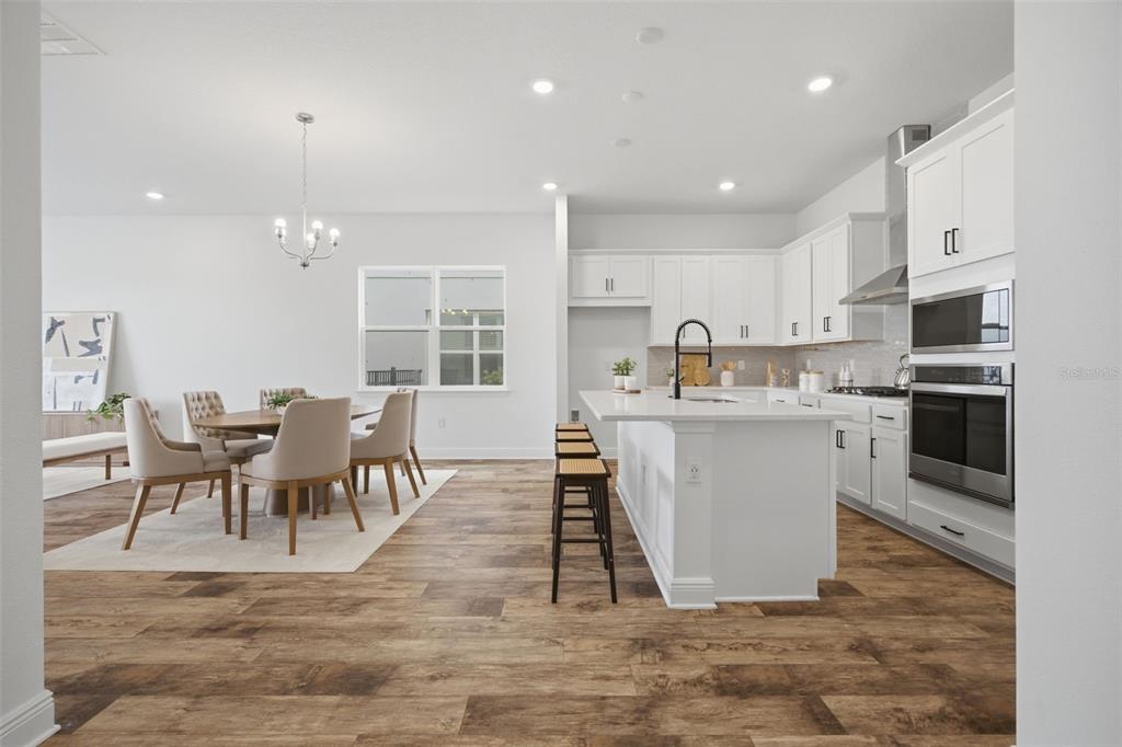 An empty room with wood-look flooring, a chandelier, and sliding glass doors to a yard — 15730 VETTA DRIVE, MONTVERDE, FL