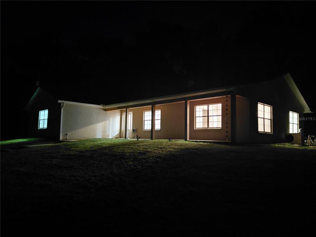 A backyard features a swimming pool with a spa adjacent to a tan house exterior — 14810 NW 185 STREET, WILLISTON, FL