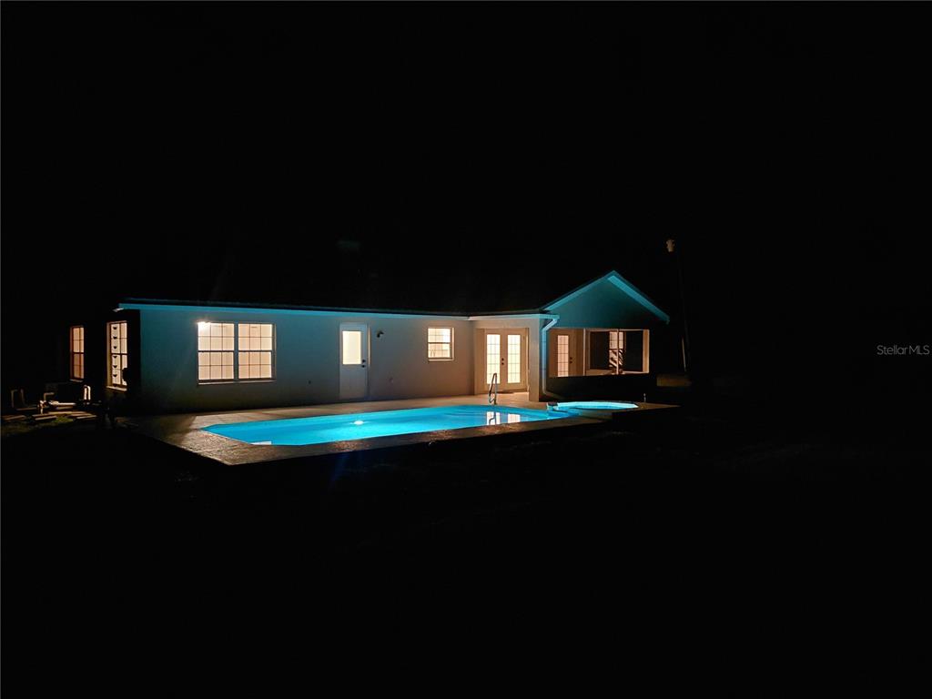 A light-colored house with a metal roof sits on a grassy lot with trees — 14810 NW 185 STREET, WILLISTON, FL