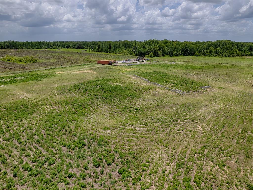 An aerial view shows a large, grassy, undeveloped lot with a small concrete foundation structure — 12005 SR-33, GROVELAND, FL