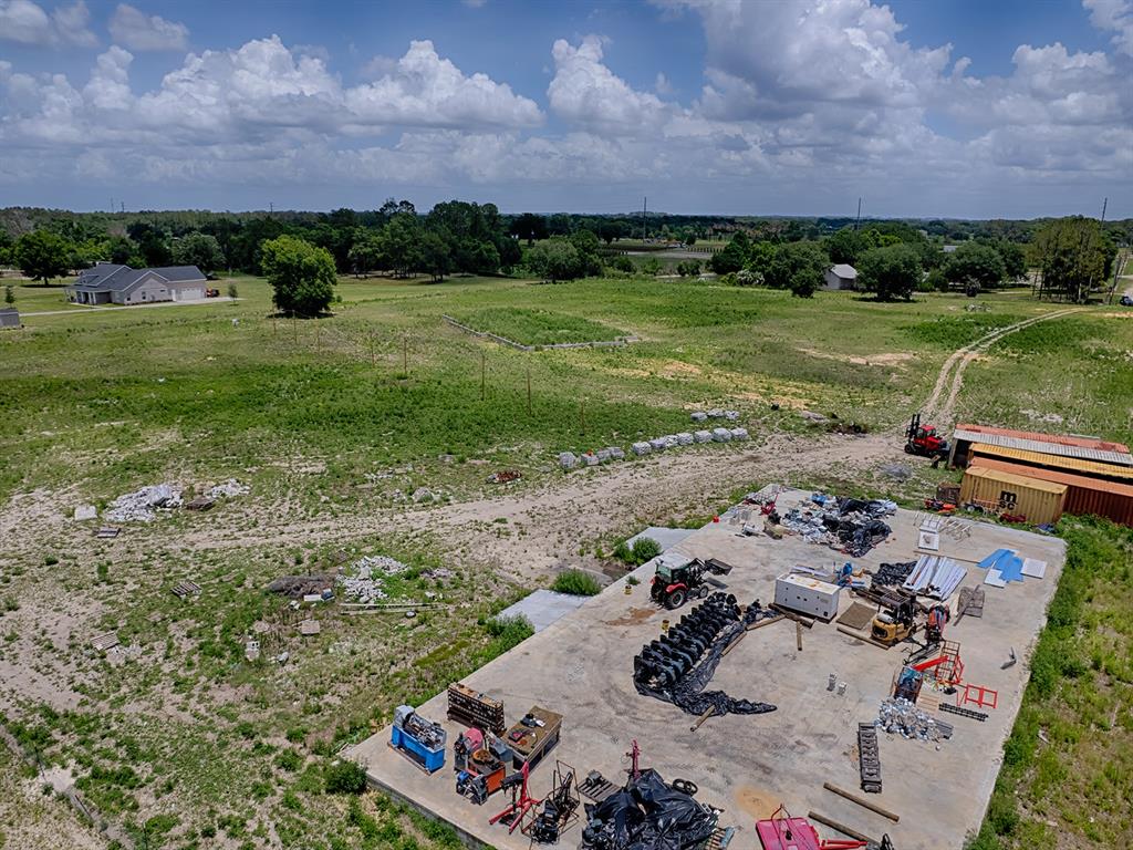 An aerial view shows a concrete pad with construction equipment and materials on a rural lot — 12005 SR-33, GROVELAND, FL