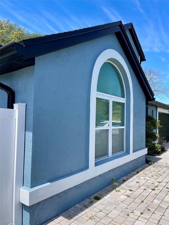 The exterior of a blue house features an arched window with white trim — 8070 VILLAGE GREEN ROAD, ORLANDO, FL