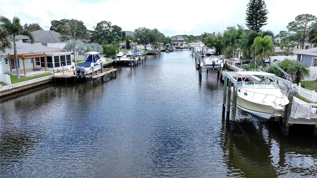 A canal view showing residential homes with private boat docks and docked motorboats — 303 MORNINGSIDE DRIVE, PALM HARBOR, FL