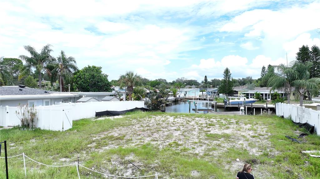 An empty, grassy waterfront lot is enclosed by white vinyl fencing — 303 MORNINGSIDE DRIVE, PALM HARBOR, FL