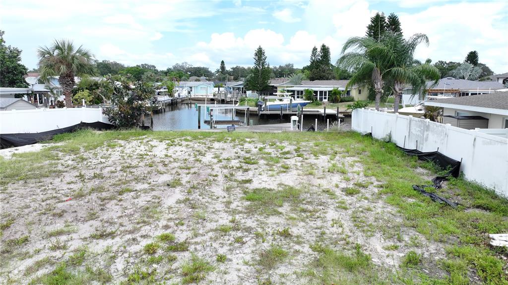 A vacant waterfront lot features sandy ground, sparse vegetation, and a private boat dock — 303 MORNINGSIDE DRIVE, PALM HARBOR, FL