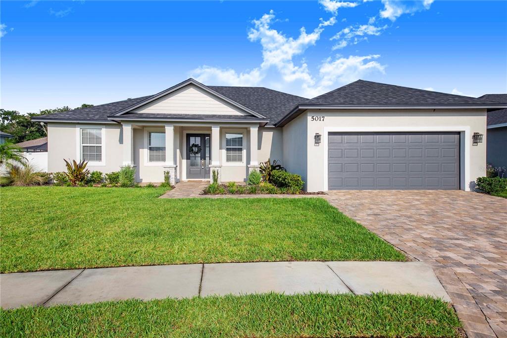 A single-story house with a gray garage, light-colored stucco exterior, and a paved driveway — 5017 RIDGEFIELD LANE, LAKELAND, FL