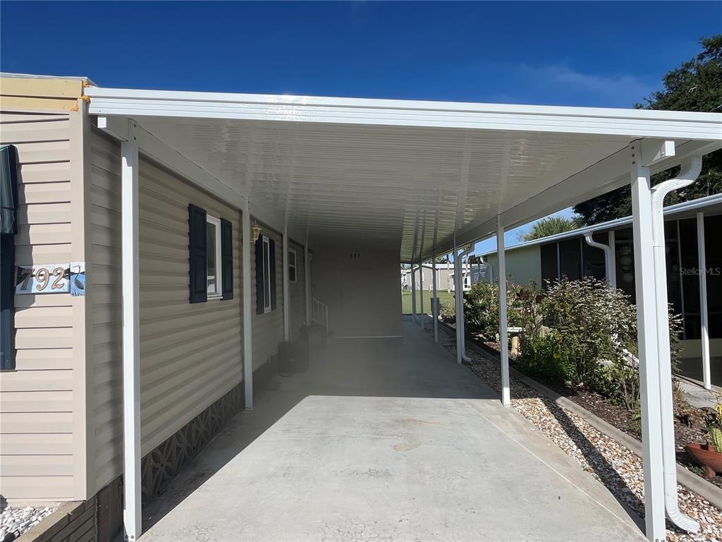 A covered carport with a concrete floor extends alongside the side of a mobile home — 792 GRADO DRIVE, VENICE, FL