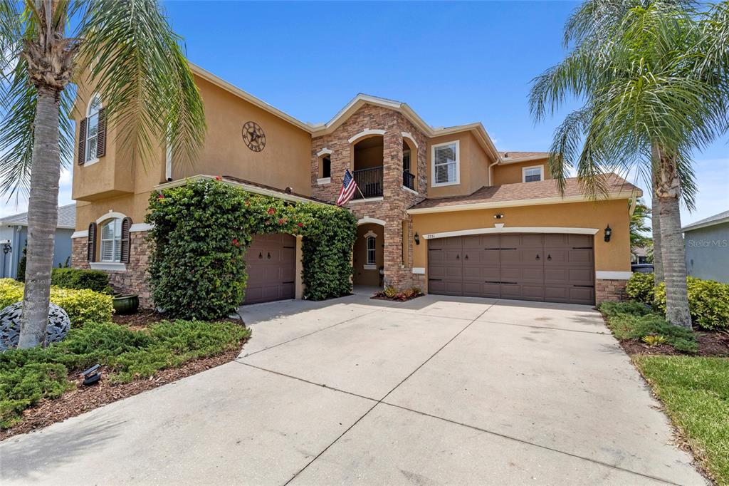 A two-story house with a stone facade, two garage doors, and a palm-lined driveway — 2351 123RD PLACE E, PARRISH, FL