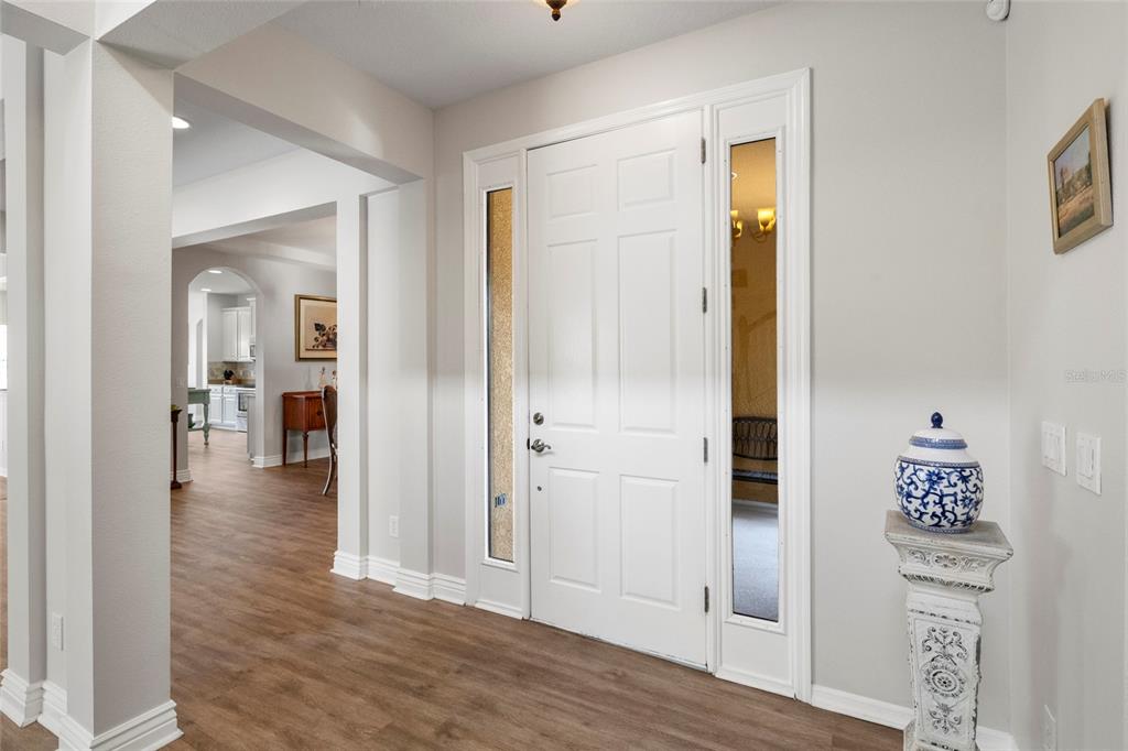 An entryway features a white front door with sidelights, wood-look flooring, and a decorative pedestal — 2351 123RD PLACE E, PARRISH, FL