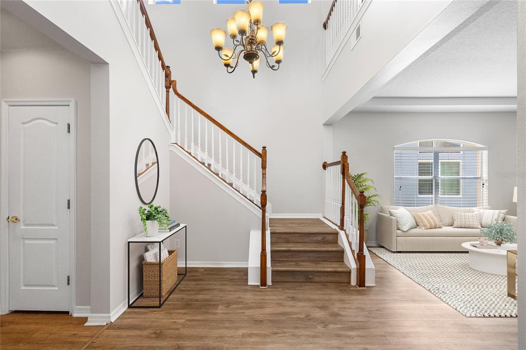 A foyer features a wooden staircase, a decorative pedestal planter, and a red velvet sofa — 2351 123RD PLACE E, PARRISH, FL