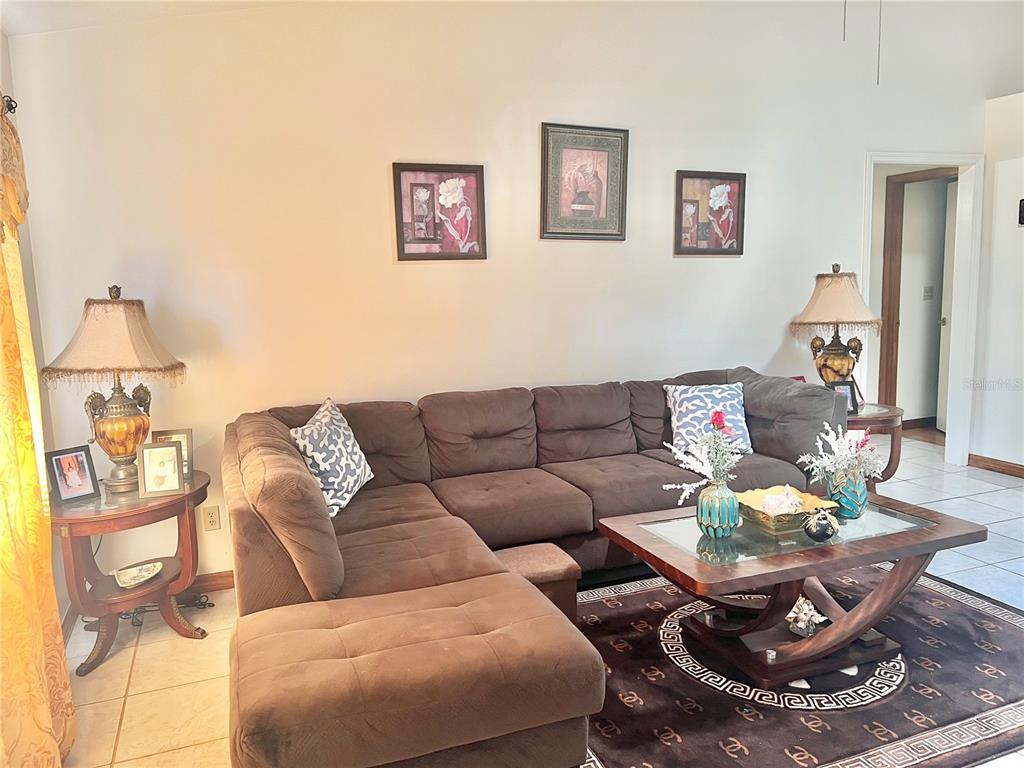 A living room features a brown sectional sofa, a glass-topped coffee table, and wall art — 16 OAK PASS LOOP, OCALA, FL