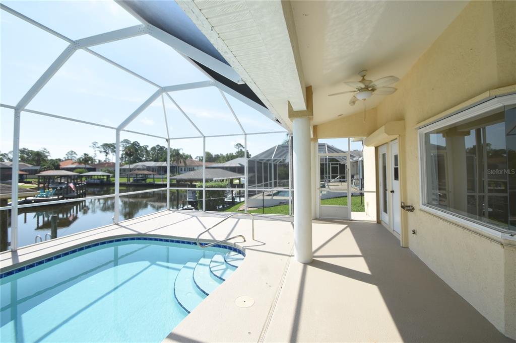 A covered patio with a swimming pool overlooks a canal with boat docks — 10 CRAMPTON COURT, PALM COAST, FL