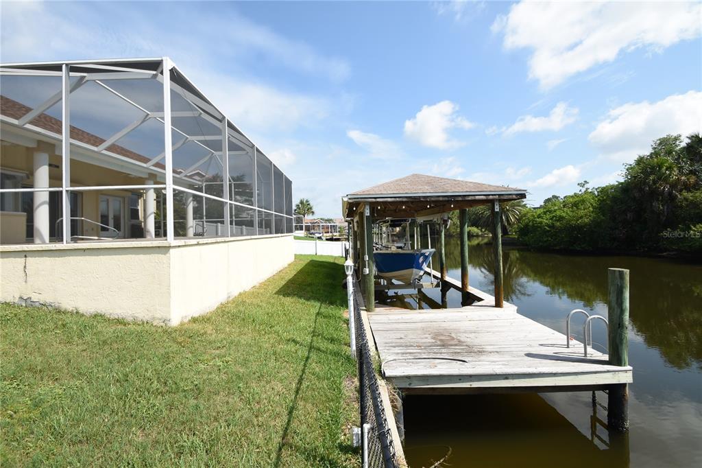 A house with a screened-in patio sits next to a wooden boat dock on a canal — 10 CRAMPTON COURT, PALM COAST, FL