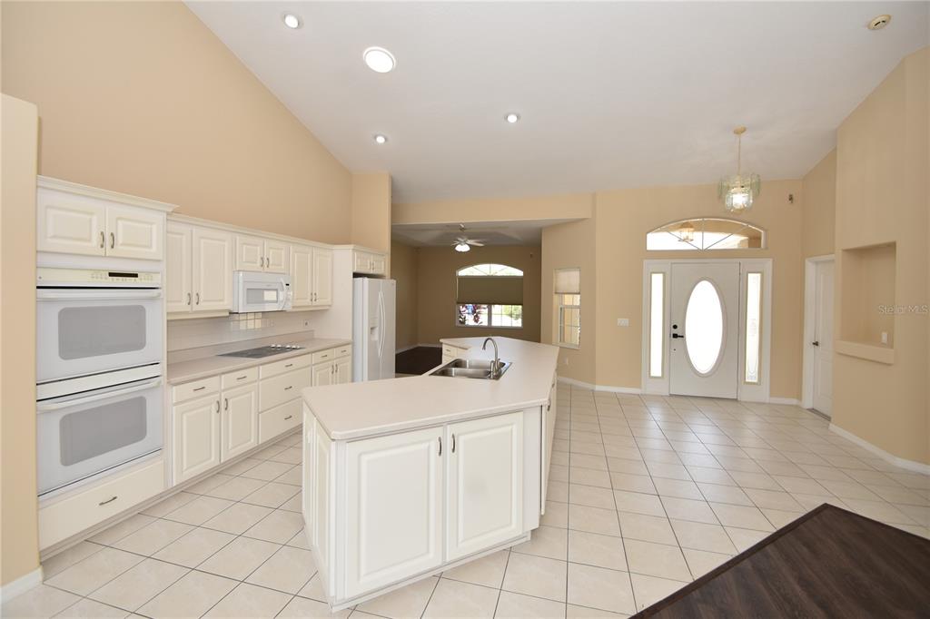 A kitchen with white cabinets, a central island, and tile flooring opens to an entryway — 10 CRAMPTON COURT, PALM COAST, FL