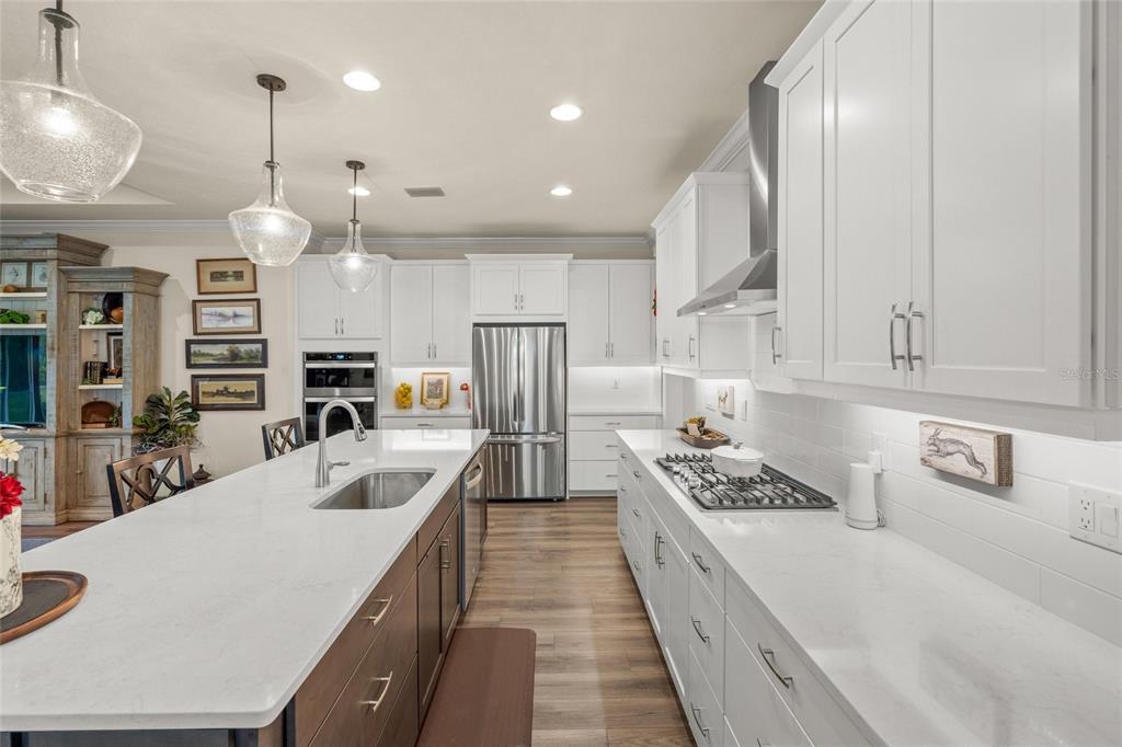 A modern kitchen features white cabinetry, a large island with a sink, and stainless appliances — 5773 LONG SHORE LOOP, SARASOTA, FL