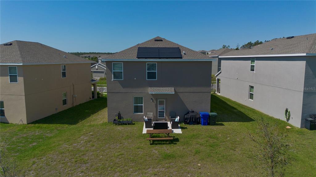 The exterior rear view of a two-story house features a small patio and solar panels — 2825 MULLER OAK LOOP, OCOEE, FL