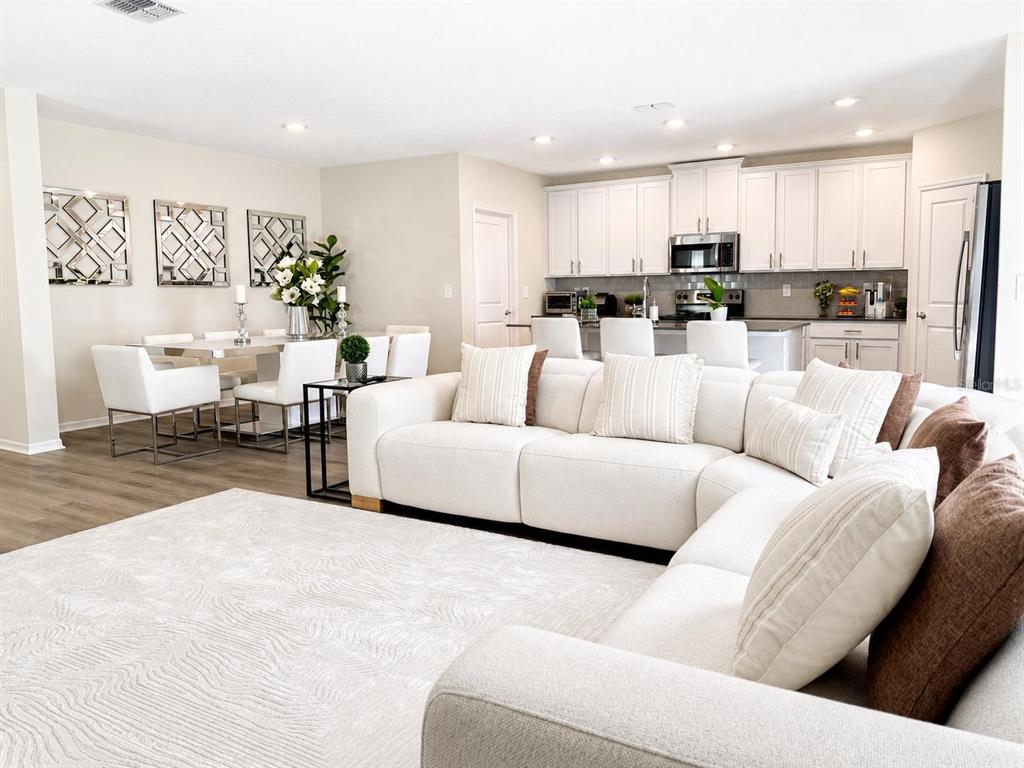 An open-concept living room and kitchen feature white cabinetry, a sectional sofa, and dining area — 2825 MULLER OAK LOOP, OCOEE, FL