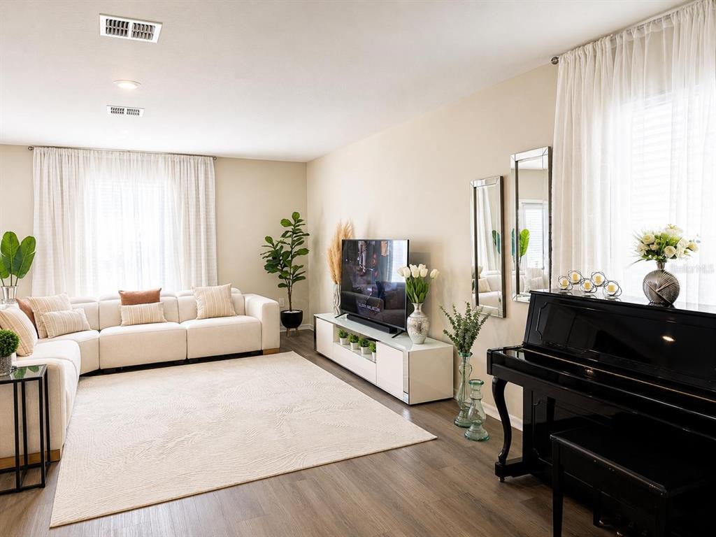 A living room features a white sectional sofa, a television on a console, and a piano — 2825 MULLER OAK LOOP, OCOEE, FL