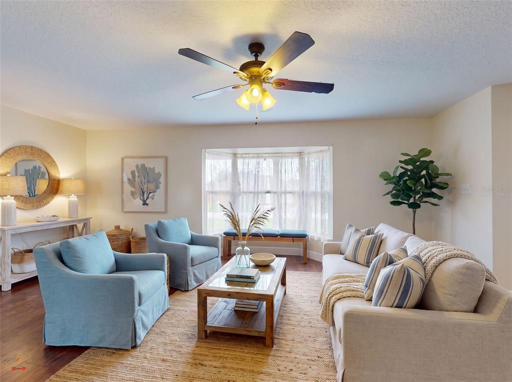 A living room features two blue armchairs, a beige sofa, a coffee table, and ceiling fan — 2125 E PARKTON DRIVE, DELTONA, FL