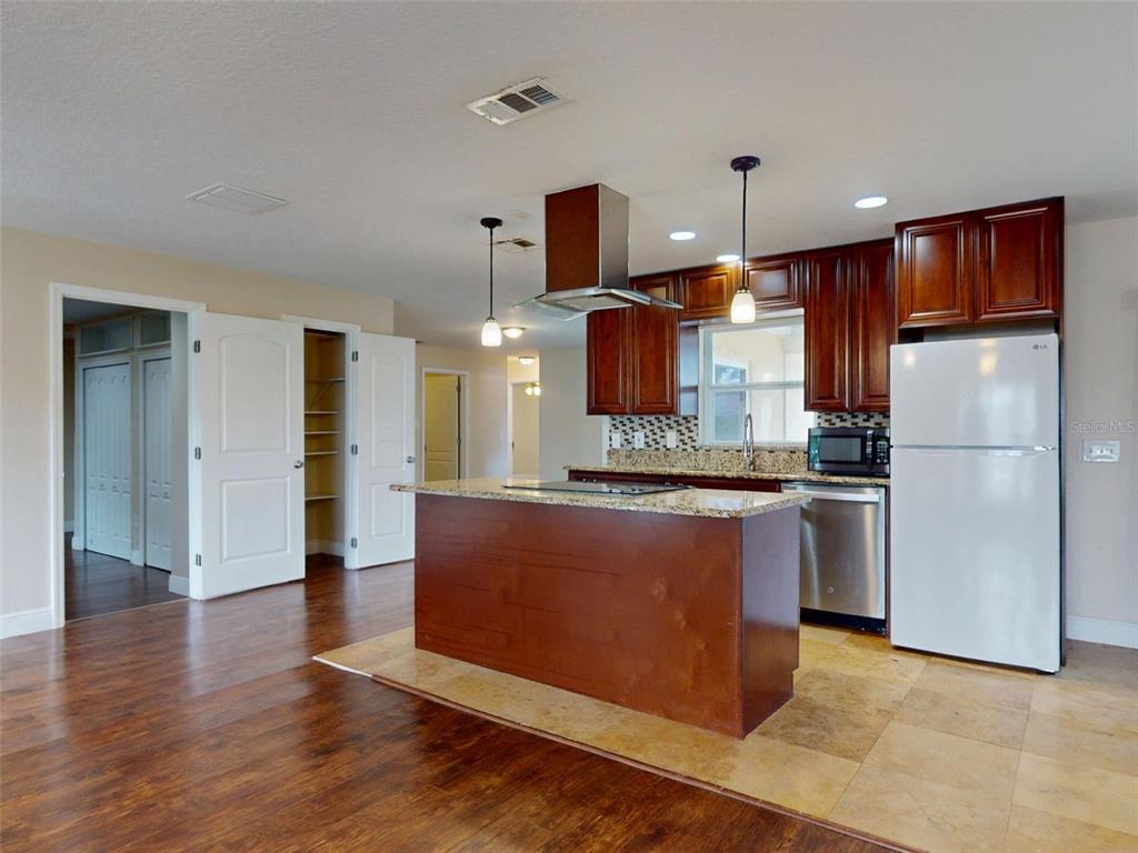 A kitchen features dark wood cabinets, a granite-topped island, stainless steel appliances, and tile flooring — 2125 E PARKTON DRIVE, DELTONA, FL