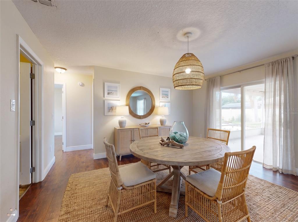 A dining room features a round wooden table, rattan chairs, and a woven pendant light — 2125 E PARKTON DRIVE, DELTONA, FL