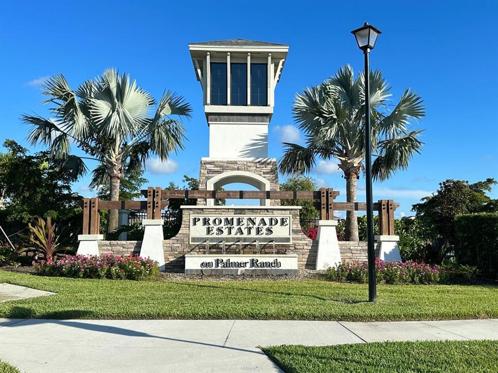 A stone entrance monument for Promenade Estates on Palmer Ranch sits between two palm trees — 12760 LATERAL ROOT DRIVE, SARASOTA, FL