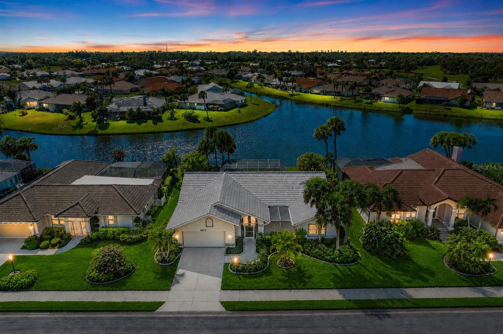 A screened-in swimming pool overlooks a lake during a sunset — 1679 VALLEY DRIVE, VENICE, FL
