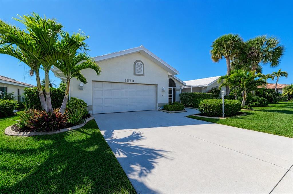 An aerial view shows a single-story house with a pool cage beside a lake — 1679 VALLEY DRIVE, VENICE, FL