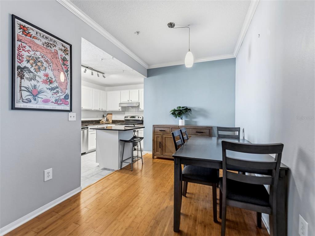 A dining area with hardwood floors leads into a kitchen featuring granite countertops and stainless appliances — 501 KNIGHTS RUN AVENUE UNIT 1325, TAMPA, FL