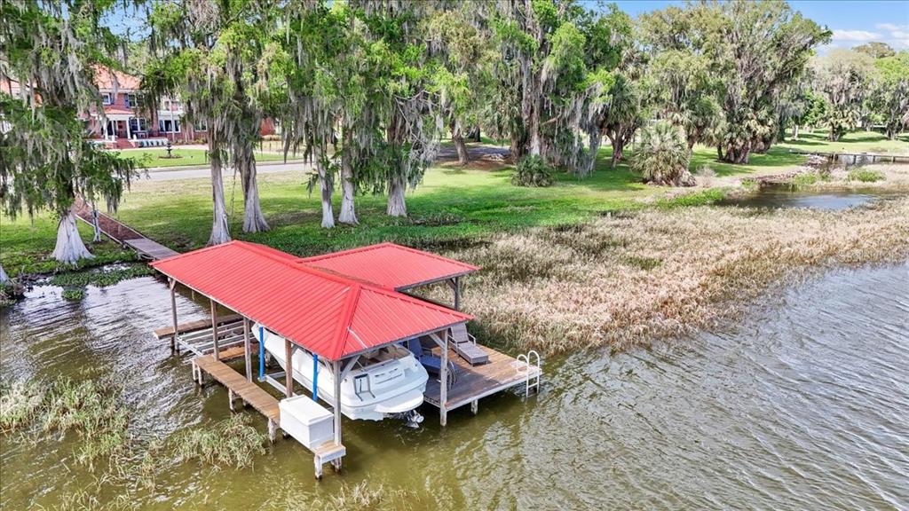 An aerial view shows a house with a red roof, pool, and a waterfront lot — 405 LAKESHORE DRIVE, LEESBURG, FL