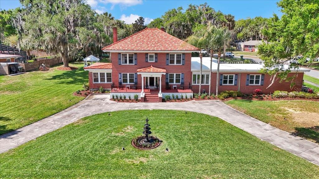 A grassy lawn leads to a wooden walkway and a covered boat dock on a lake — 405 LAKESHORE DRIVE, LEESBURG, FL