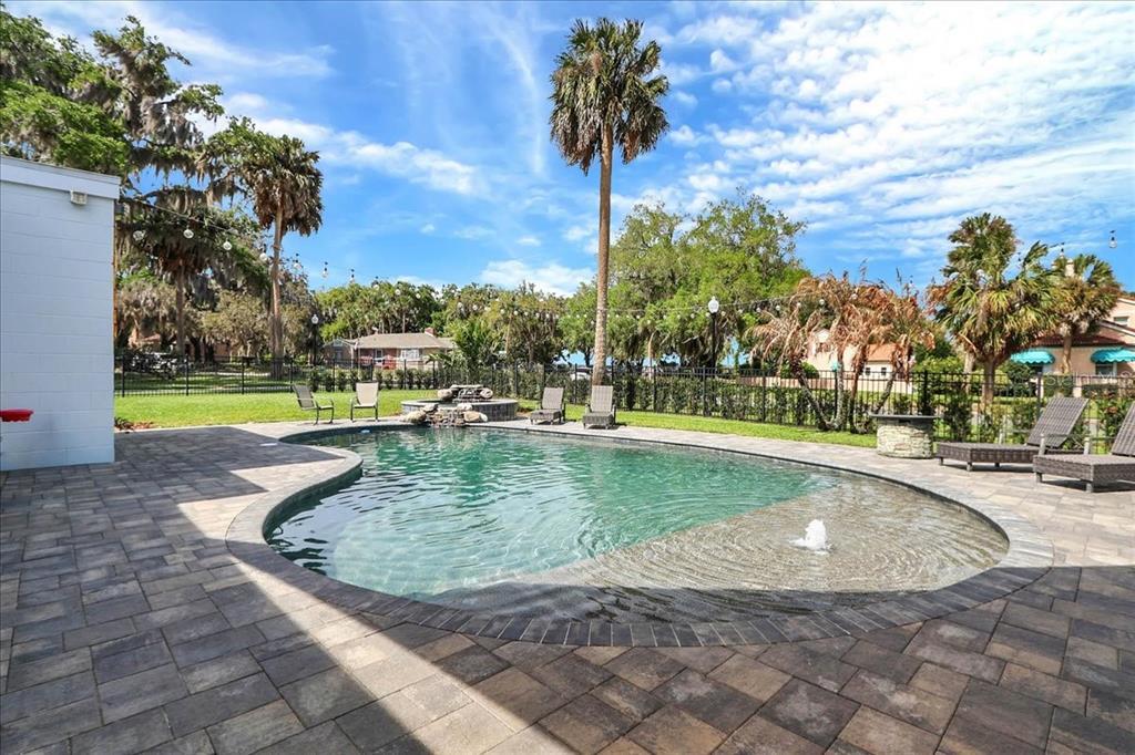A backyard features a kidney-shaped swimming pool with a fountain and stone paver patio — 405 LAKESHORE DRIVE, LEESBURG, FL