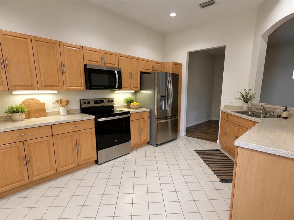 A kitchen with light wood cabinets, stainless steel appliances, and white tile flooring — 39905 BAYVIEW DRIVE, LADY LAKE, FL